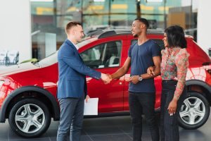young african couple buying new car at dealership